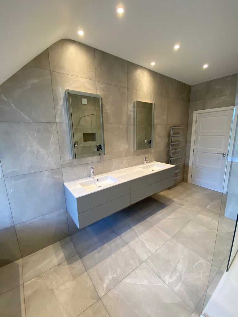 Modern bathroom with large wall mirror, double sink vanity, glass shower enclosure, and recessed ceiling lights