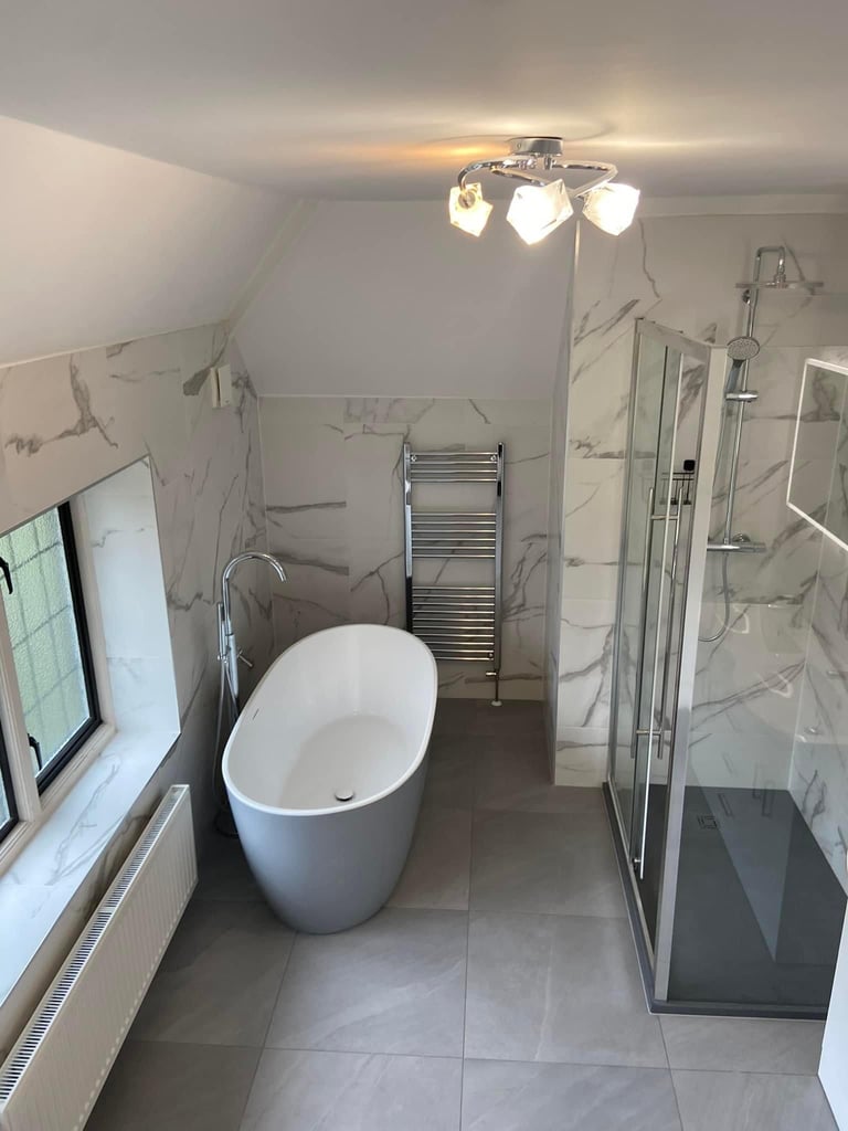 Modern bathroom with freestanding bathtub, walk-in shower, heated towel rail, and ceiling lights in marble-tiled space